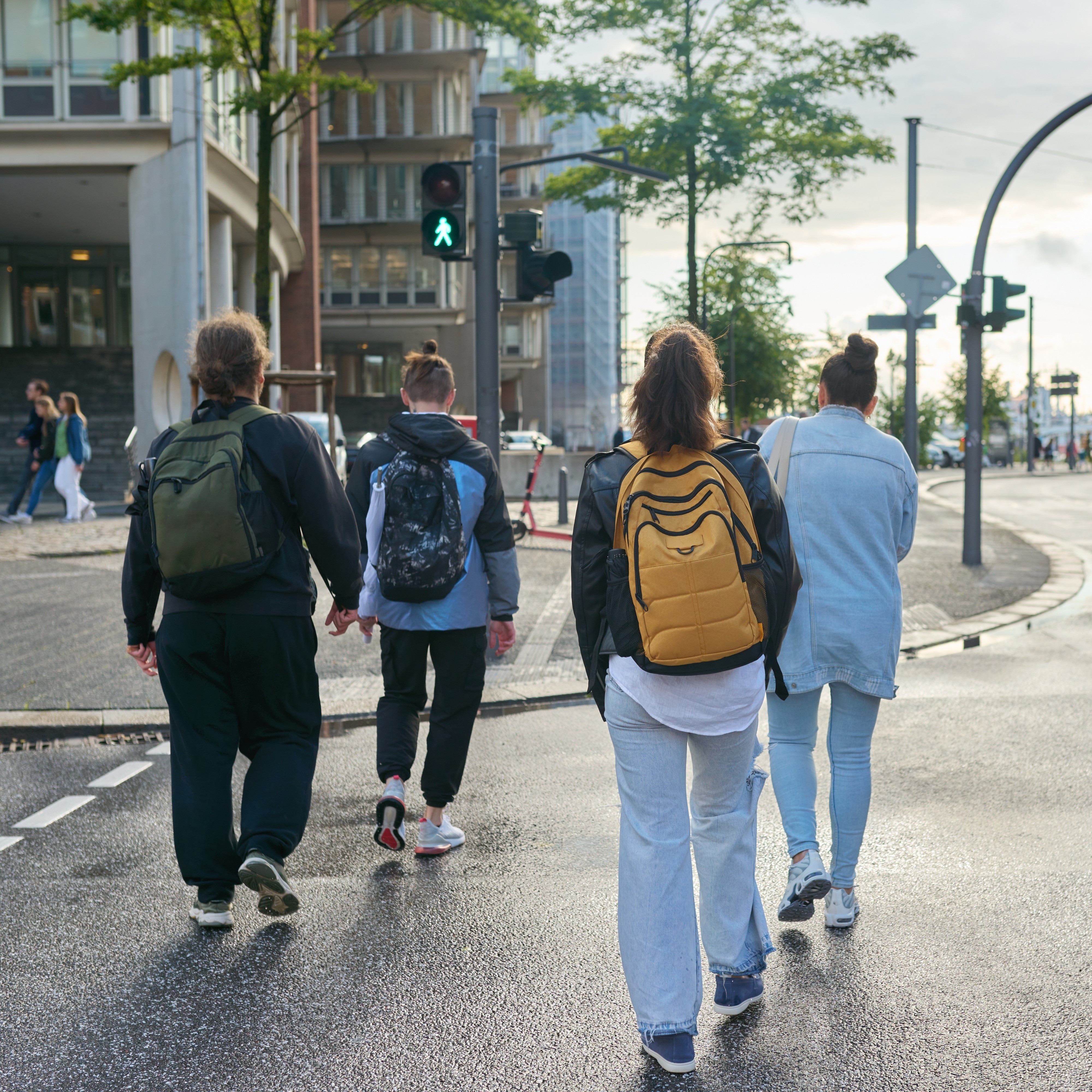 Eine Gruppe junger Erwachsener überquert eine Straße an einer grünen Fußgängerampel. 