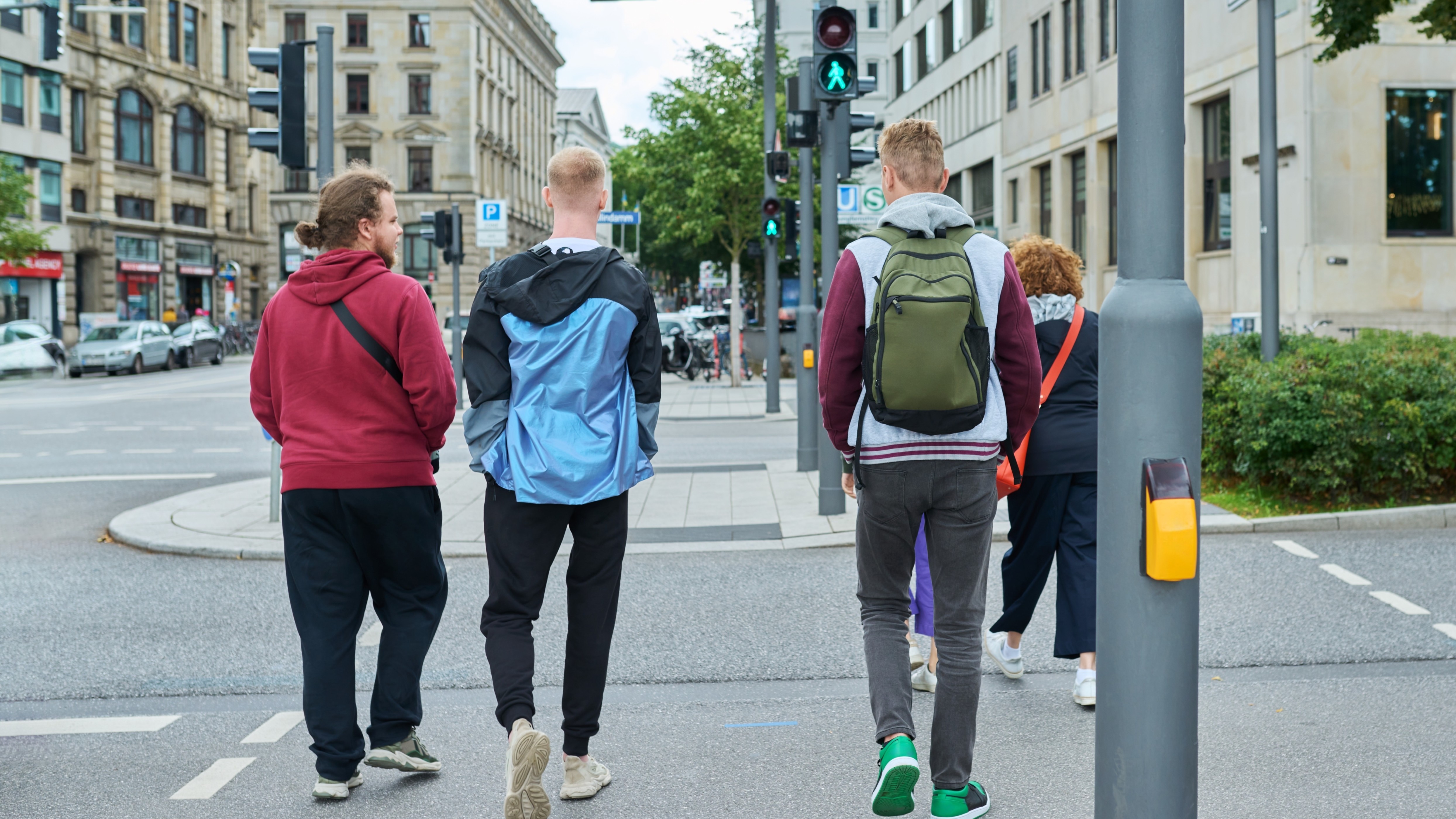 Eine Gruppe junger Erwachsener überquert eine grüne Fußgängerampel